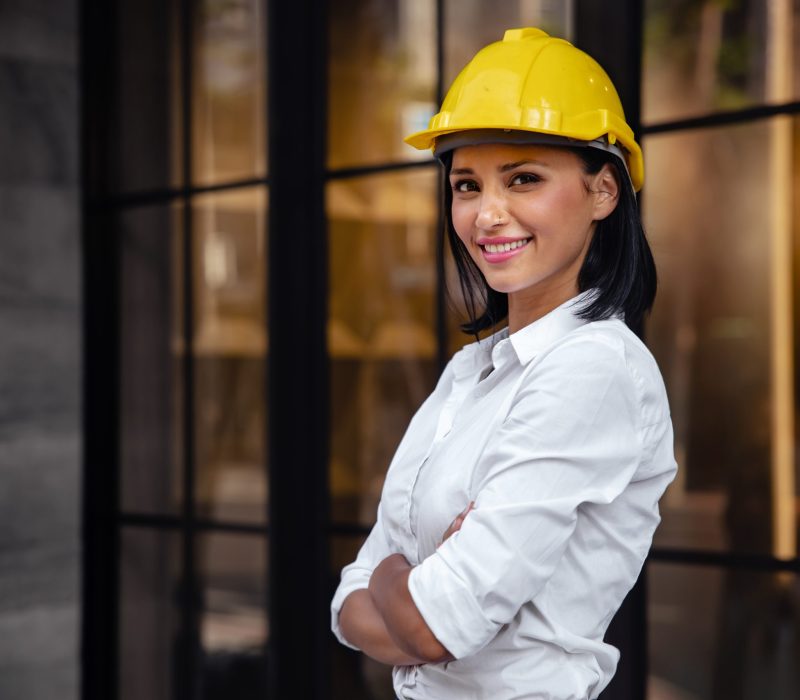 Portrait of a Confident Construction Engineer Woman. Smiling and Looking at Camera. Standing in front of the Modern Office Building